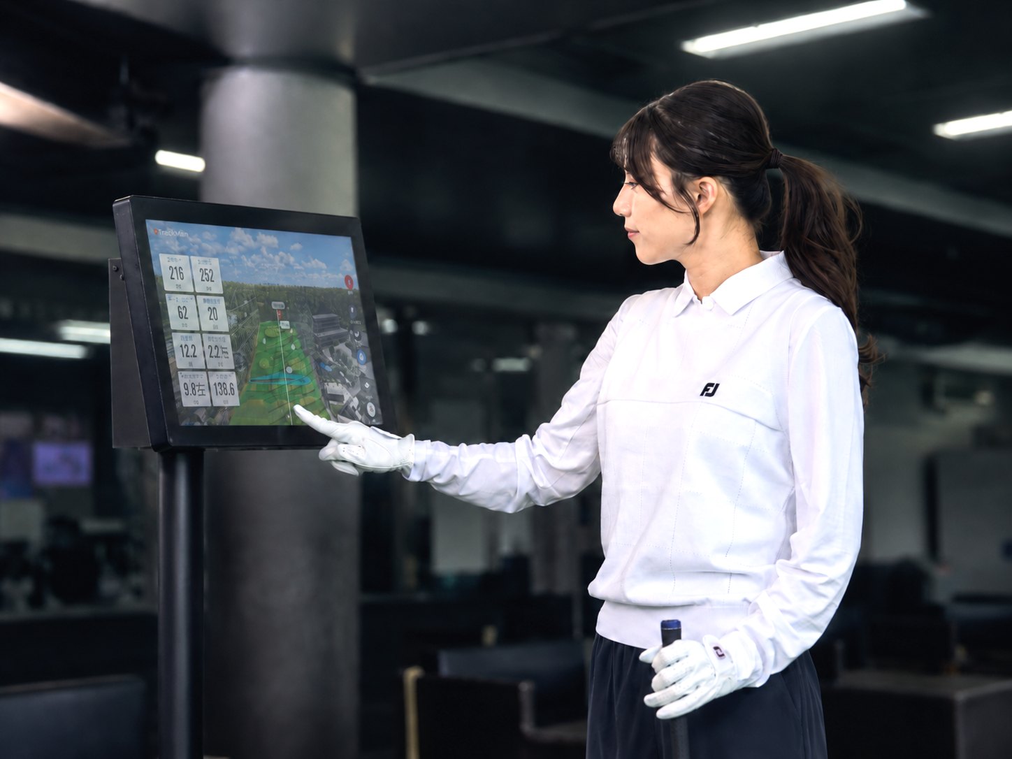 打席のTRACKMANモニターに表示された弾道データを確認するゴルファー